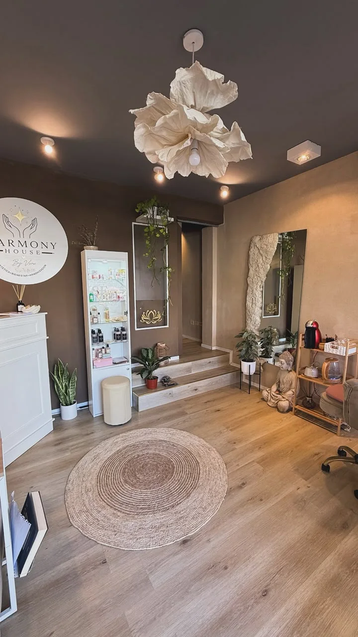 Recepción de Harmony House: paredes color moka, lámpara de papel con forma de flor, vitrina blanca con productos, alfombra redonda de yute y un Buda sobre el piso de madera
